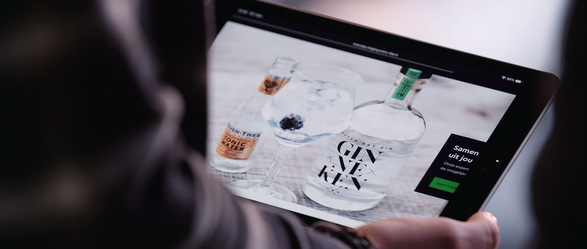 Tablet toont ginflessen en een cocktailglas op een website.