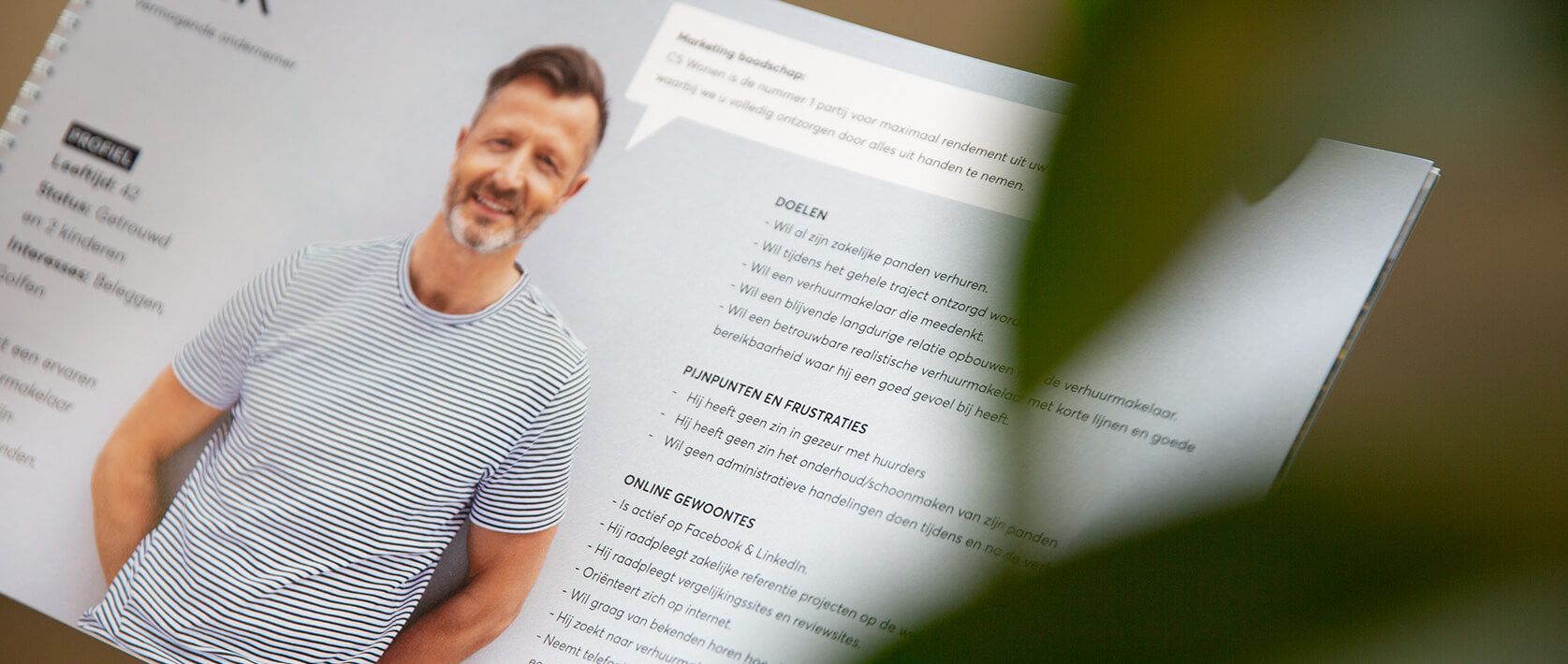 Close-up van de brochure: man in een gestreept shirt, met "Campagnes" gemarkeerd en een vleugje plantenbladeren om de sfeer te versterken.