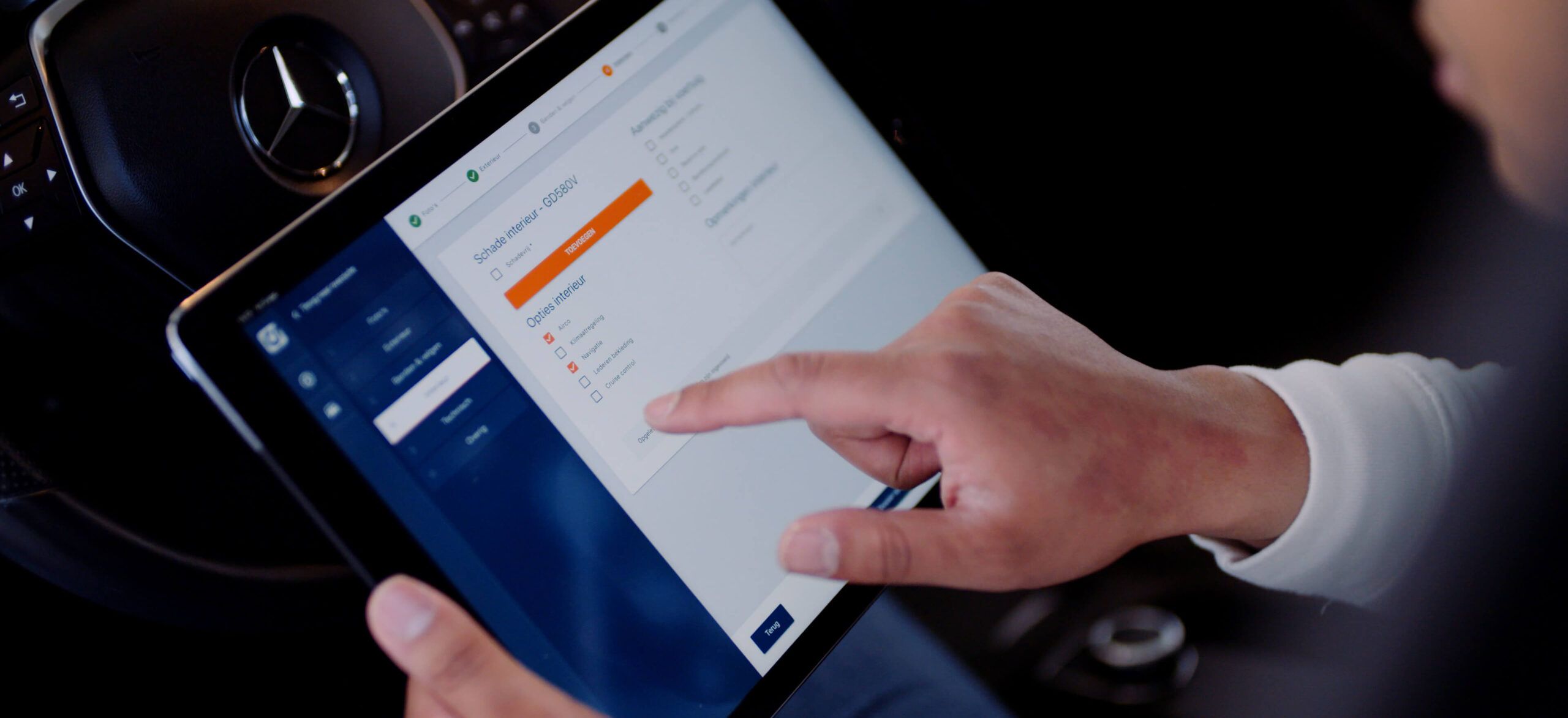 In de auto navigeert een gebruiker vakkundig op een tablet om instellingen te wijzigen. Zo combineert hij zijn liefde voor technologie met het verzamelen van auto's.