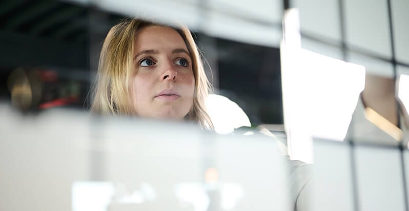 Een geconcentreerd persoon schrijft op een glazen bord, de weerspiegelingen in zijn vastberaden uitdrukking.