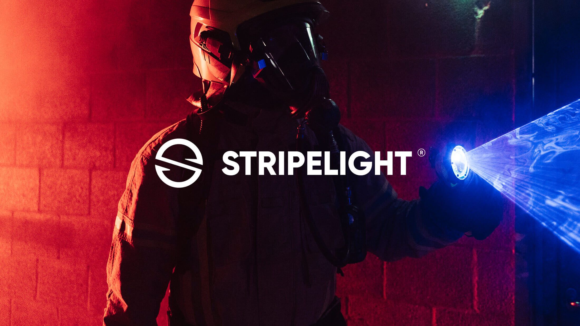 Een brandweerman met een Stripelight-zaklamp werpt een blauw licht in de duisternis; het STRIPELIGHT-logo is zichtbaar.