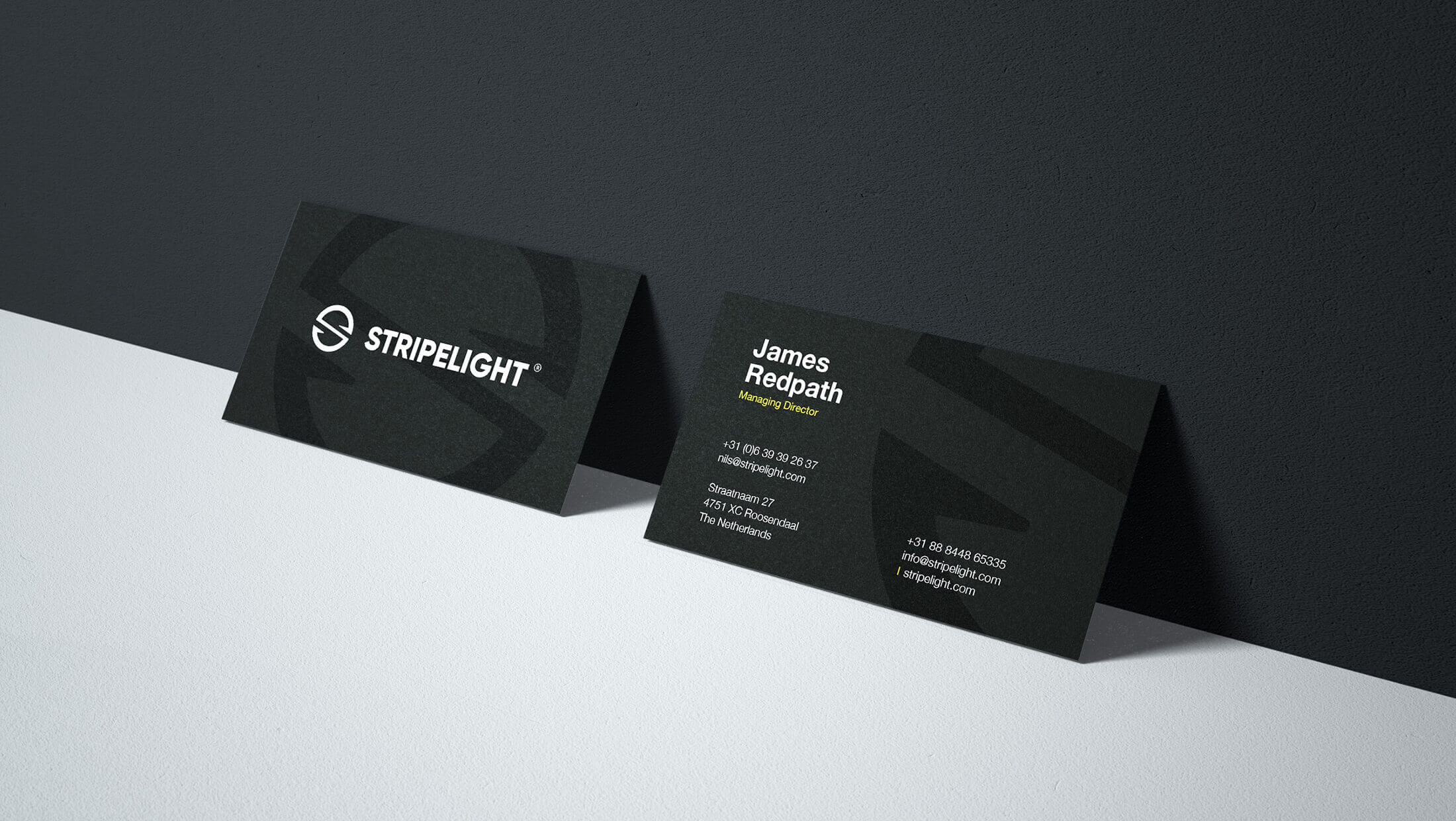 Twee strakke, zwarte visitekaartjes, één met een logo en de ander met witte contactgegevens, die oplichtten als een zaklamp.