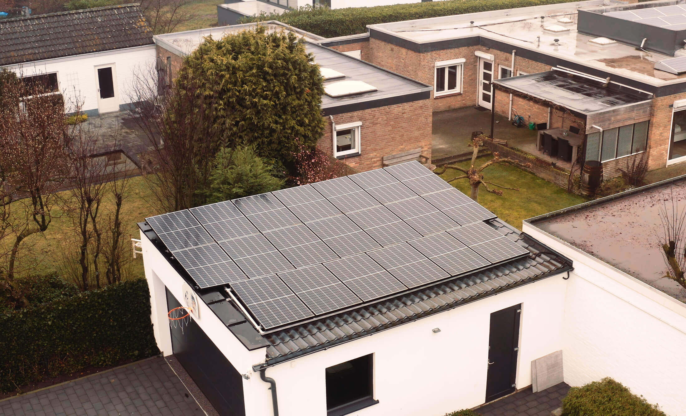 YMX Euro Solar panelen schitteren op een garage en versmelten met de bomen en verzorgde gazons in de buitenwijk.