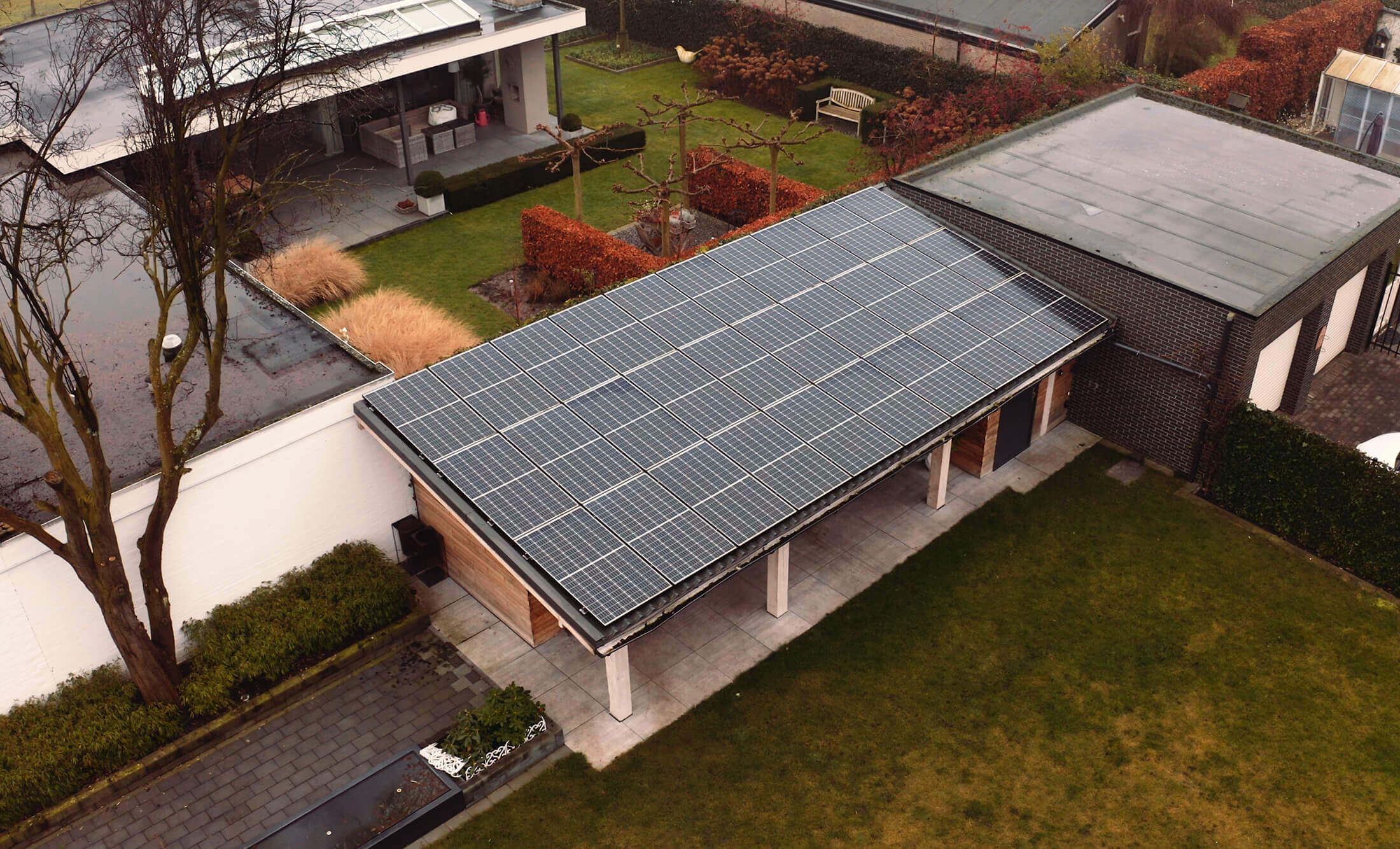 Luchtfoto: YMX Euro Solar-panelen zijn verweven met het dak van een huis, omgeven door weelderige tuinen en bomen.