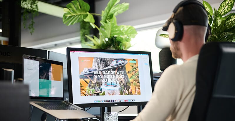 Koptelefoon op, werkend op een computer met een levendig webdesign, omringd door weelderige planten.