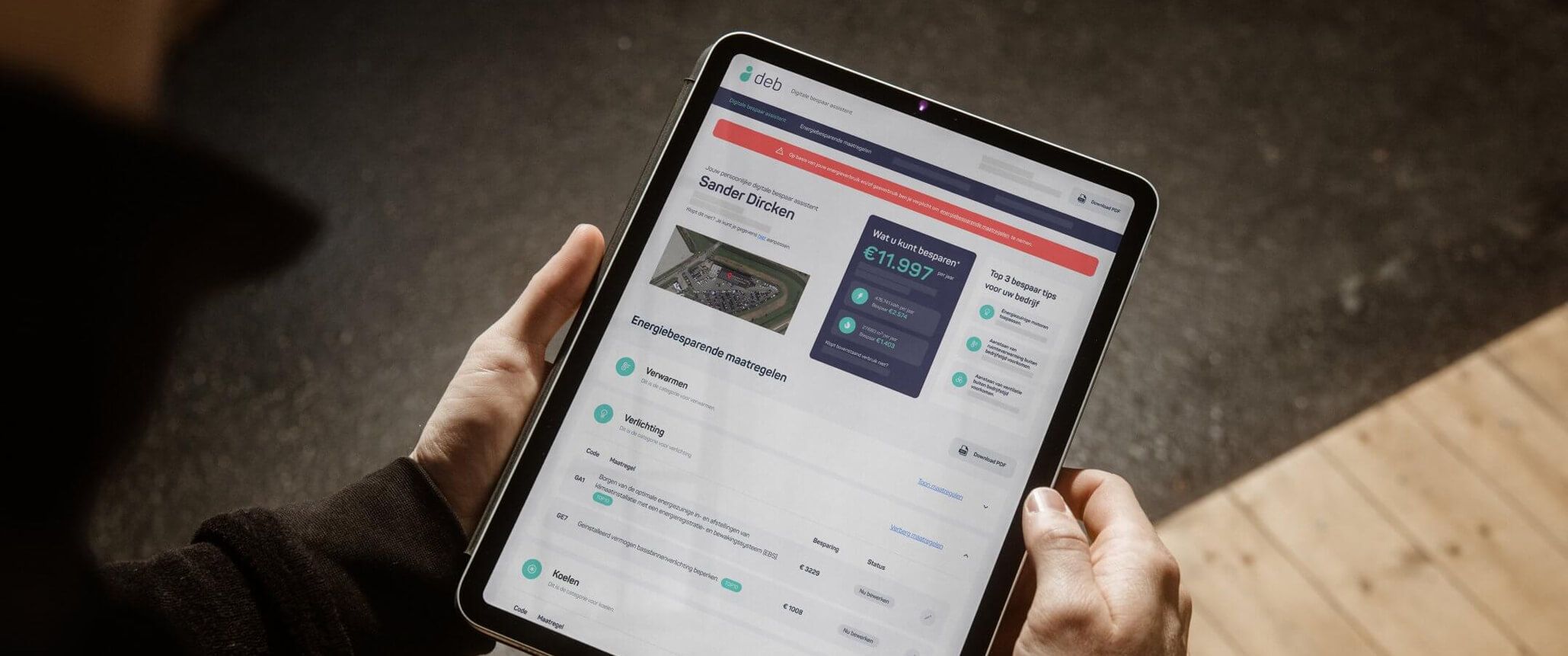 Gebruiker met tablet die een financiële app met grafieken en statistieken toont.