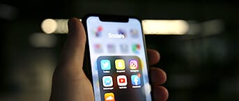 Een hand houdt een telefoon vast, het scherm vol met apps voor sociale media, waarmee de digitale branding wordt benadrukt.
