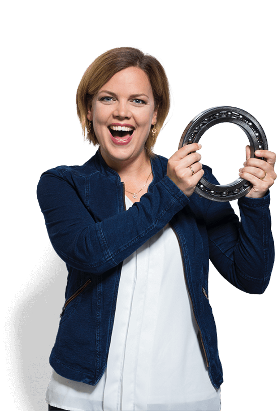 Een vrouw in een blauw jasje toont met een glimlach een ABF-onderdeel en toont daarmee haar technische vaardigheden.